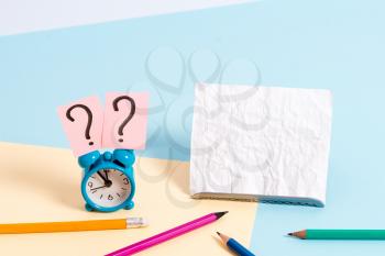 Mini size alarm clock beside stationary placed tilted on pastel backdrop