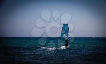 Holiday concept image with the blue sea and the blue sky. Man on the surfing board riding on the waves. Action sports on the water waves. Surfer on the surfing board.