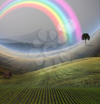 Peaceful Landscape with Mountain and rainbow. Giant moon rises at the horizon. Horse grazes in the field