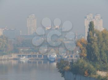Panorama of the autumn city in a haze of fog over the river