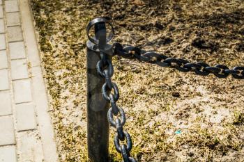 Close up of black chains barrier stand in the city park.