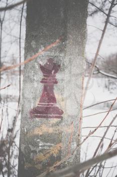 A chess piece of a queen is stamped on a cement pillar in the park.