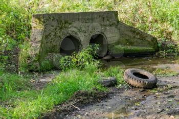 Large old concrete drain pipe, culvert in the grass.