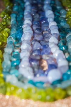 Natural stone small beads of tanzanite, agate, aquamarine, apatite and peridot close up.