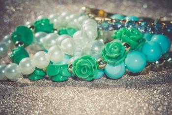 Stylish fashion bracelets with blue beads and pearls on glittering background.