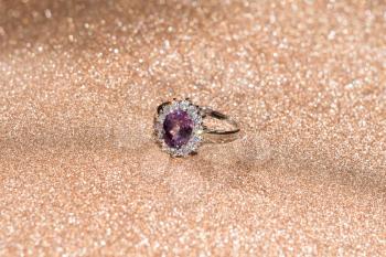Fashion silver ring with purple amethyst on glittering background.