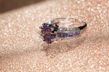 Fashion silver ring with purple amethyst on glittering background.