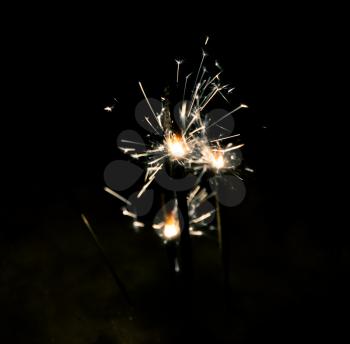 Colorful bright holiday bengal fires, sparks on the dark background.