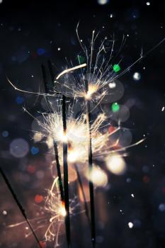 Bengal fire, sparkler and colorful bokeh in a shape of a heart, holiday background.