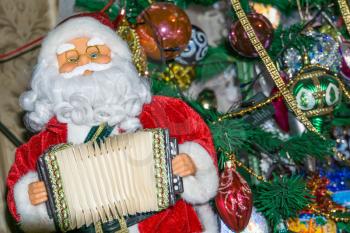 Christmas santa toy playing the accordion, holiday background.