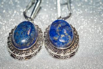 Vintage silver earrings with natural stone, blue lapis lazuli background.