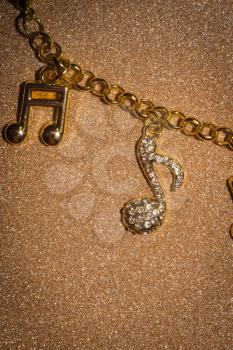 Fashion bracelet with decorative gold charms in a shape of a music note background.
