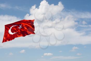 Turkish national flag with white star and moon in cloudy sky