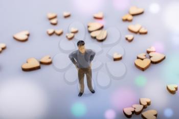 Wooden hearts  around a man figurine on white background