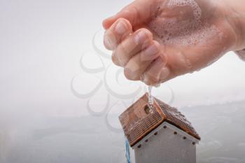 Hand holding a model house in foamy water