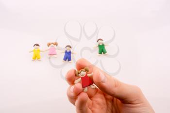 Hand holding colorful dressed children figure on a white background