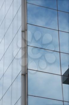 Sky mirrored on the windows of a modern glass building. Architectural detail.