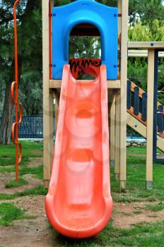 Red plastic slide at a kids playground.