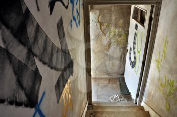 Painted arrow on staircase pointing to exit door in an abandoned house.