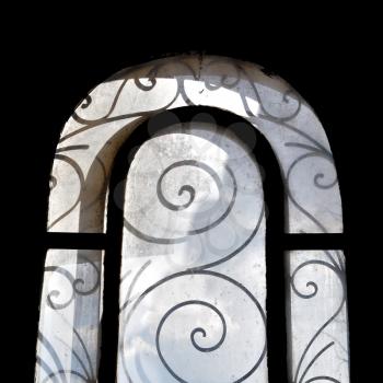 Sunlight on dusty arched window with vintage decorative metalwork motif.