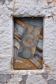 Boarded up window frame of an old house and rough wall background texture.