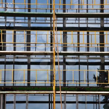 Facade windows and iron scaffold detail. Modern glass building under construction.