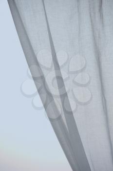 Window curtain against the sky. Folded textile abstract background.