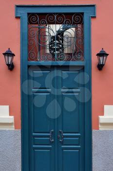 Blue wooden door with antique wrought iron pattern. Architectural detail.