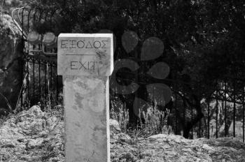 Sign pointing to the exit from the archaeological site of Acropolis in Athens, Greece. Black and white.