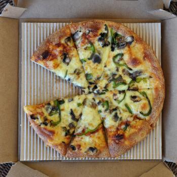 Takeaway pizza with mushrooms and green pepper in cardboard box. Italian fast food background. 
