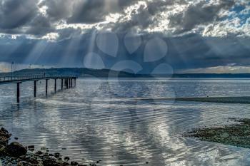 Rays of light shine through clouds in Des Moines, Washington. HDR image.