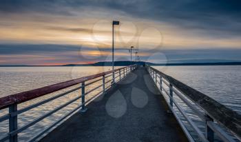 A veiw of the pier in Des Moines, Washington at sunset. The sky is cloudy.