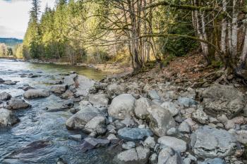 Trees and rocks line the shore along the  Snoqualmie River in Washington State.