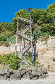 A vertical staircase rises straight up next to a hill at Saltwater State Park in Des Moines, Washington.