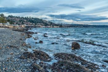 A view of the shoreline at low tide in West Seattle, Washington. It is a stormy day.