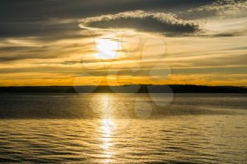 A view of the sun setting on the Puget Sound creating a dark golden glow.