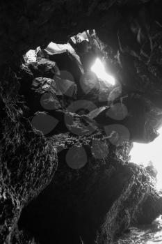 White light shines into a sea cave on Maui, Hawaii. Black and white image.