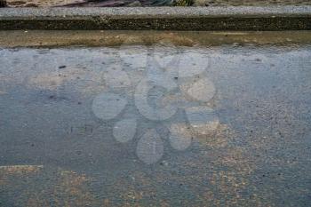 A vackground shot of rain hitting a cement sidewalk.