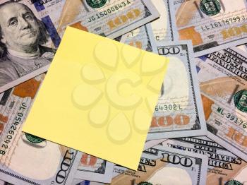 American cash money with Benjamin Franklin and blank yellow sticky note aerial view