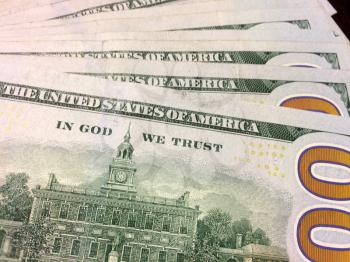 Multiple dollar bills reading In God We Trust and Independence Hall