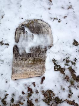 Old cemetery gravestones with snow on cold winter day