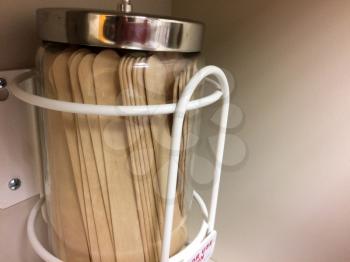 Wooden Tongue depressors in glass jar on wall