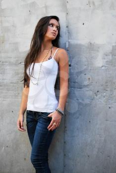 Sexy beautiful female brunette long hair jeans urban concrete background white wall