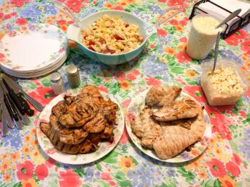 chicken fillets on barbecue tabl with sauce and lines coleslaw macaroni salad
