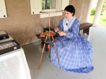 lady in period costume makes human hair jewelry horse hair