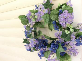 purple flower wreath of plastic hanging outdoor on white