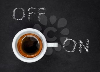 Top view of a Espresso Coffee in small white cup with a lettering ON and OF on black slate background