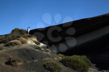 Young man waiving from a mountain with clear blue sky on the background