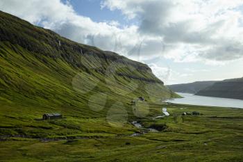 Landscape of Faroe Islands showing a farm surrounded by green mountains and fjord