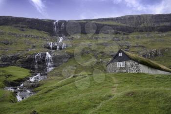 Saksun, Faroe Island - 18 September: Typical hut with grass roof and waterfall